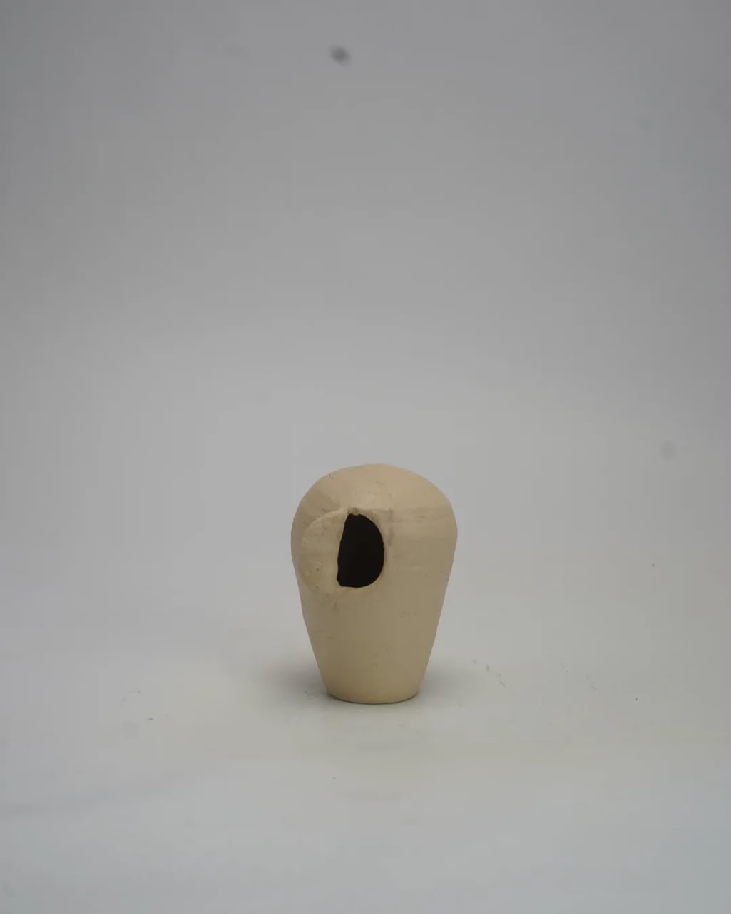 Large hand-built smoked clay vessel standing in a bare studio