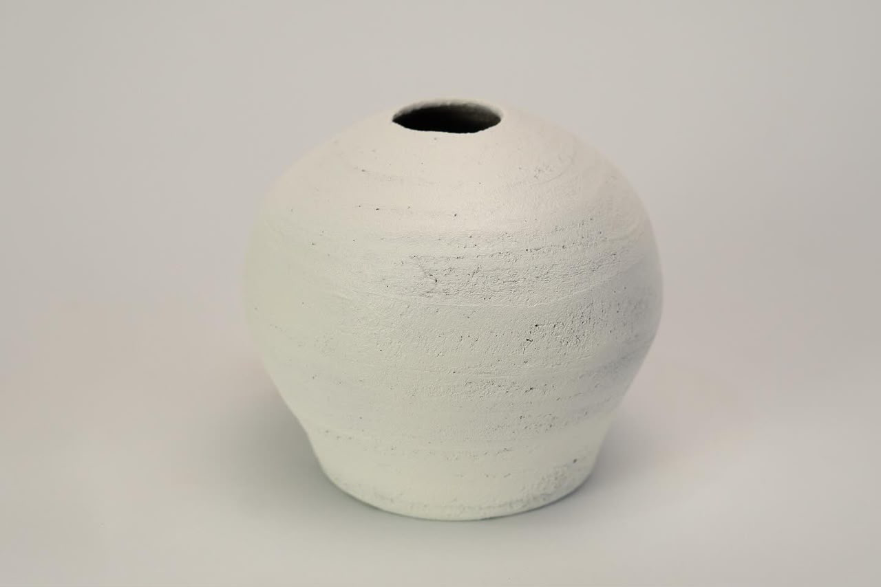 Round white vessel with a small dark mouth